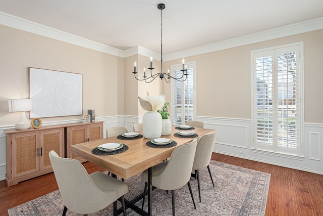 dining room featuring a wainscoted wall, crown molding, wood finished floors, and a notable chandelier