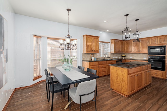 kitchen featuring wood finish floors, dark countertops, decorative backsplash, a sink, and black appliances