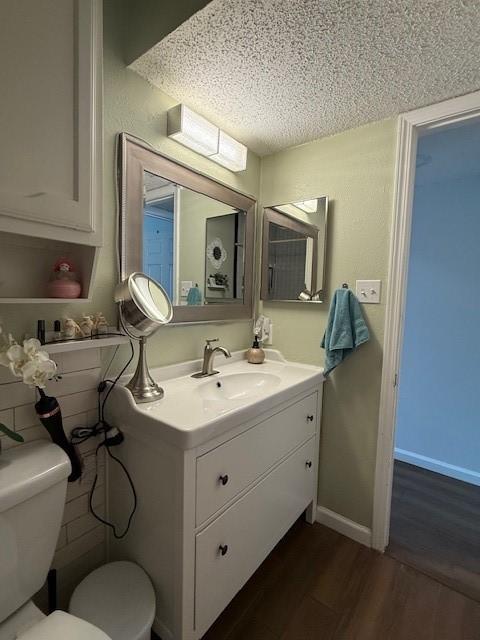 bathroom with baseboards, vanity, toilet, and wood finished floors