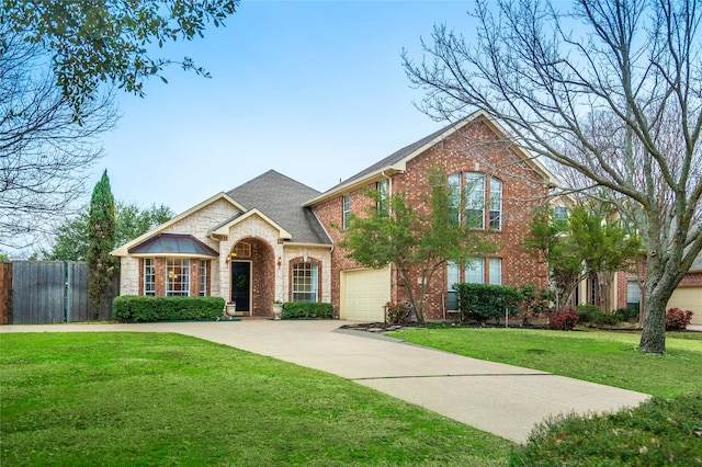 view of front of house featuring brick siding, concrete driveway, fence, stone siding, and a front lawn