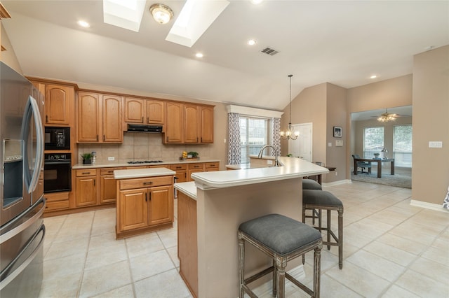 kitchen featuring black appliances, a center island with sink, visible vents, and extractor fan