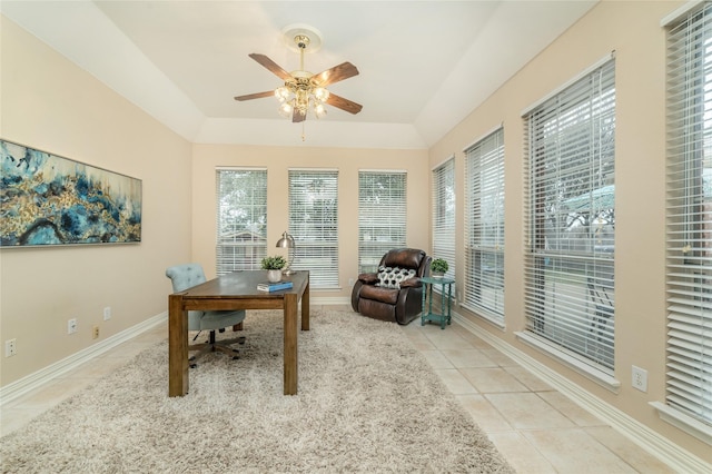 home office featuring a tray ceiling, ceiling fan, baseboards, and light tile patterned floors