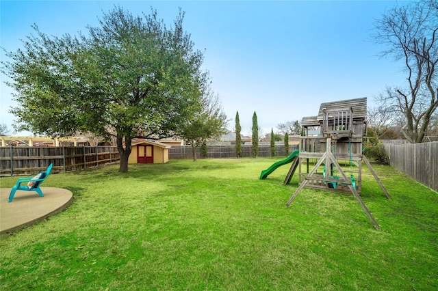 view of play area featuring a storage unit, a lawn, an outdoor structure, and a fenced backyard