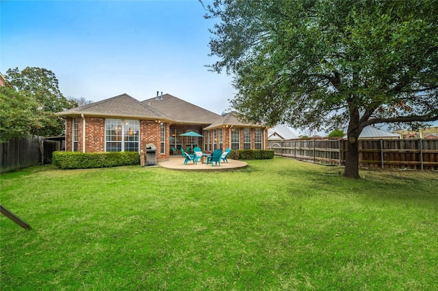 rear view of property with a yard, a fenced backyard, a patio, and brick siding