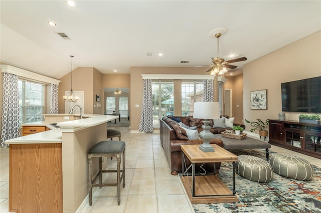 living area with vaulted ceiling, light tile patterned floors, ceiling fan with notable chandelier, and visible vents