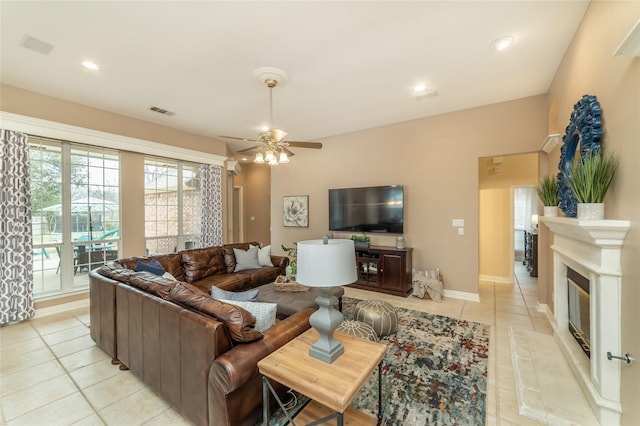 living area featuring light tile patterned floors, visible vents, a glass covered fireplace, ceiling fan, and recessed lighting