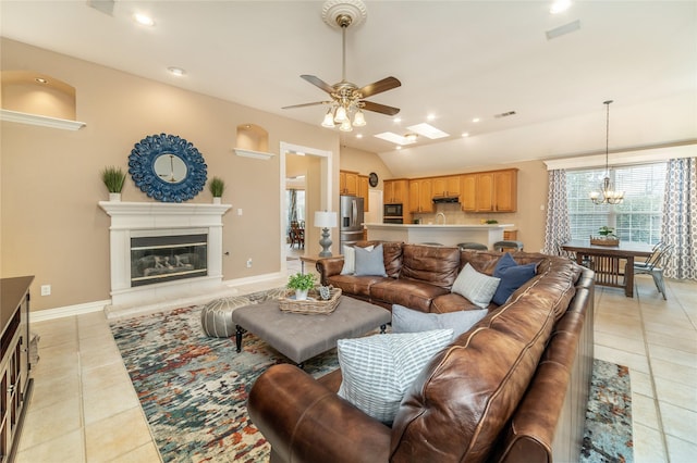 living area with light tile patterned floors, baseboards, visible vents, a glass covered fireplace, and vaulted ceiling