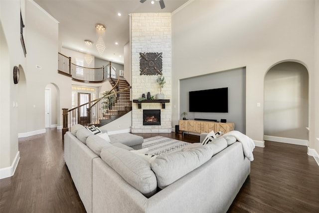 living room featuring dark wood-type flooring, arched walkways, a fireplace, and stairway