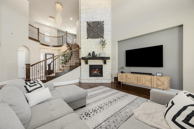 living room featuring stairs, a fireplace, wood finished floors, and baseboards