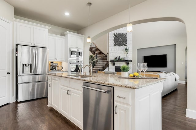 kitchen with light stone countertops, stainless steel appliances, dark wood-type flooring, and open floor plan