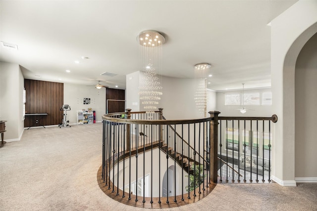 hallway featuring carpet, visible vents, an inviting chandelier, an upstairs landing, and baseboards