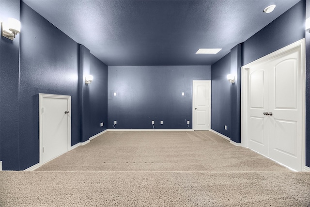 spare room featuring carpet, baseboards, and a textured ceiling