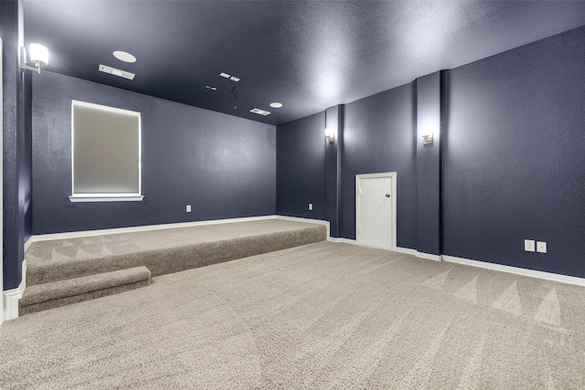 carpeted empty room featuring visible vents, a textured wall, a textured ceiling, and baseboards