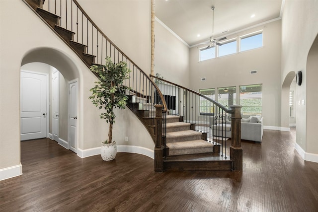 staircase with arched walkways, wood finished floors, visible vents, baseboards, and ornamental molding