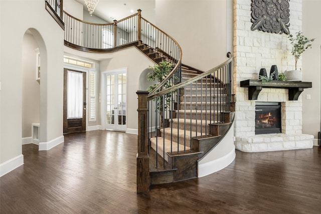 entrance foyer with baseboards, wood finished floors, a high ceiling, stairs, and a fireplace