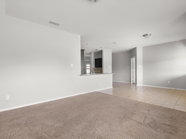 interior space featuring light carpet, light tile patterned flooring, visible vents, and baseboards