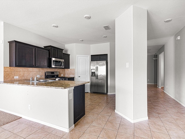 kitchen featuring a sink, visible vents, appliances with stainless steel finishes, backsplash, and light stone countertops