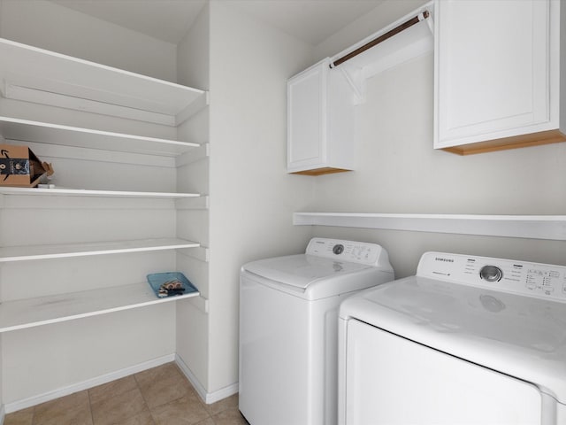 washroom featuring cabinet space, baseboards, washer and dryer, and light tile patterned flooring