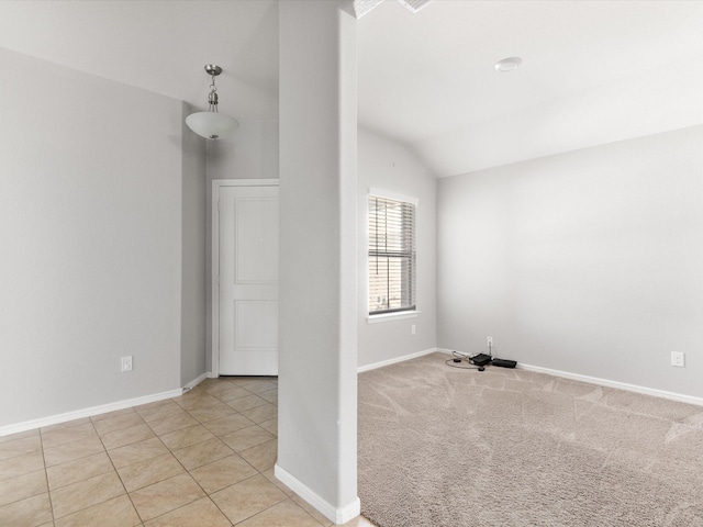 tiled spare room featuring lofted ceiling, carpet flooring, and baseboards