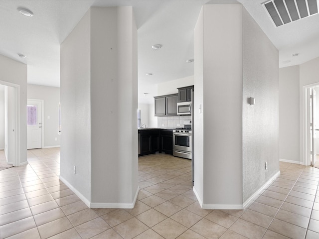 hallway featuring light tile patterned floors, visible vents, and baseboards