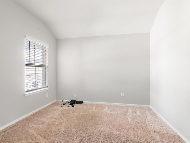 carpeted spare room with vaulted ceiling and baseboards