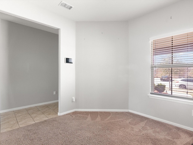 unfurnished room featuring baseboards, visible vents, and light colored carpet