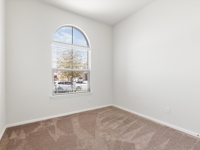 carpeted spare room featuring baseboards