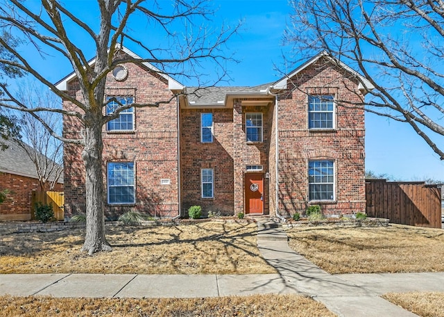 traditional-style home with fence and brick siding