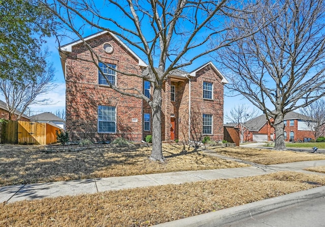 traditional-style home featuring brick siding and fence