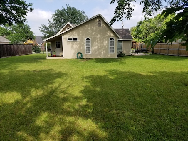 back of house featuring a patio, a lawn, and a fenced backyard