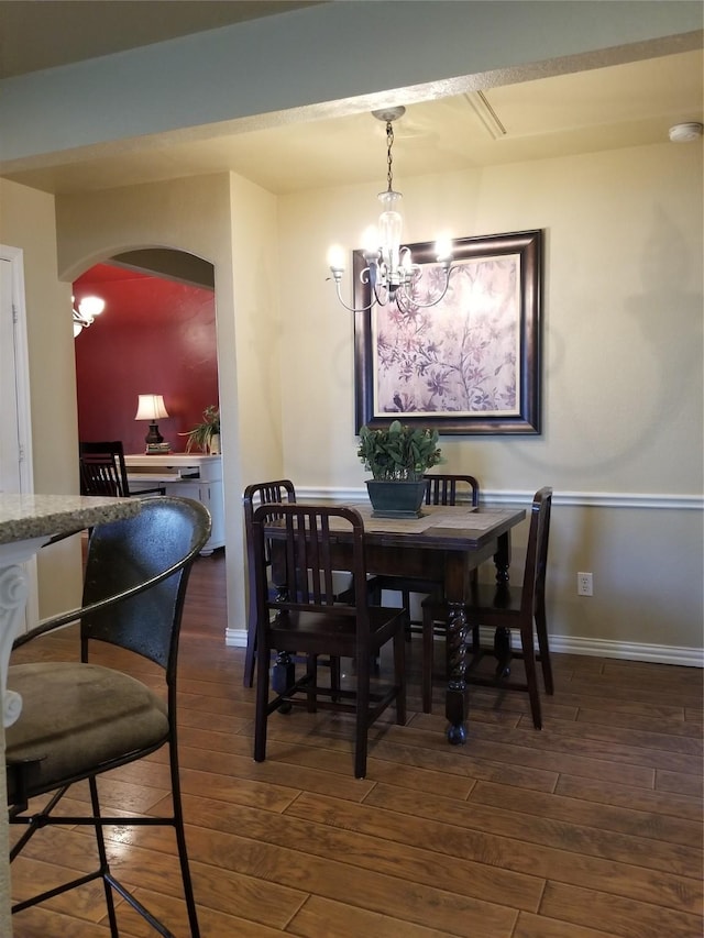 dining room featuring baseboards, arched walkways, a chandelier, and wood finished floors