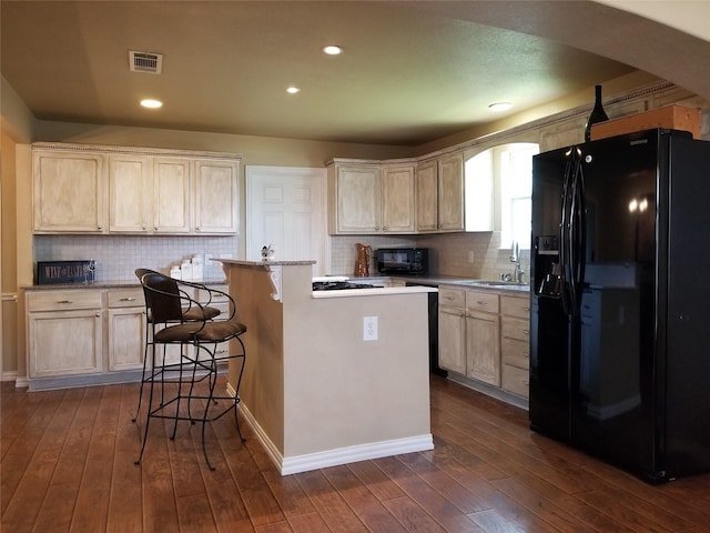 kitchen featuring dark wood finished floors, visible vents, a sink, and black appliances