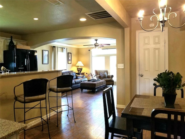 dining area with visible vents, arched walkways, dark wood-style flooring, ceiling fan with notable chandelier, and recessed lighting