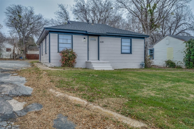 bungalow-style home featuring roof with shingles and a front lawn