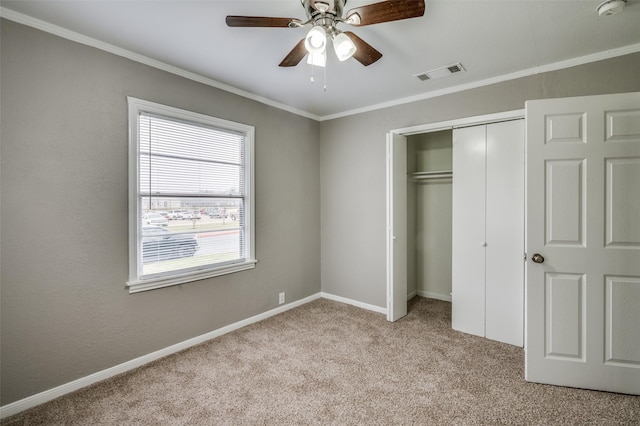 unfurnished bedroom with light colored carpet, visible vents, baseboards, a closet, and crown molding