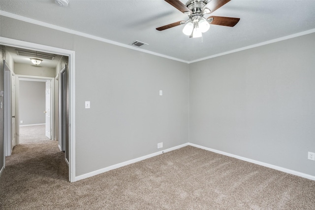 spare room with carpet floors, visible vents, crown molding, and baseboards