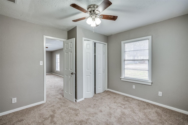 unfurnished bedroom with a textured ceiling, a textured wall, baseboards, a closet, and carpet