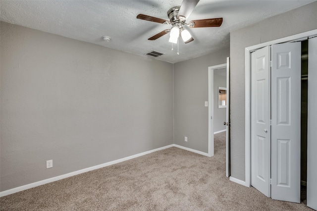 unfurnished bedroom with a textured ceiling, a closet, carpet, and visible vents