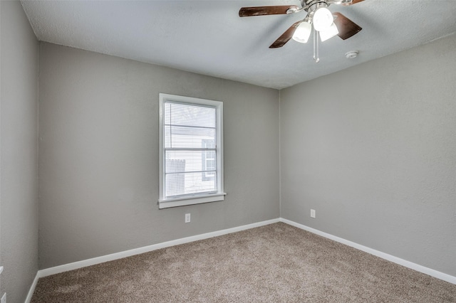 carpeted empty room with ceiling fan and baseboards