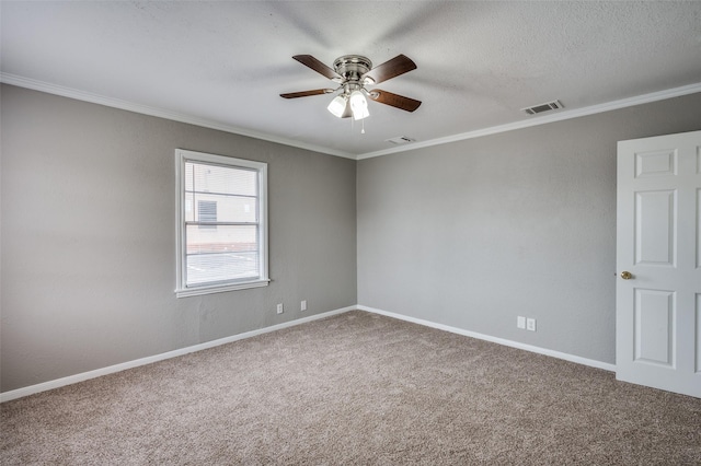 carpeted empty room with baseboards, ceiling fan, visible vents, and crown molding