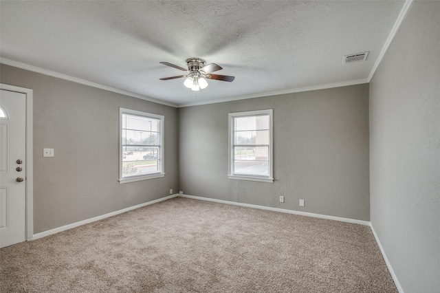 spare room with visible vents, a textured wall, ornamental molding, a textured ceiling, and carpet floors