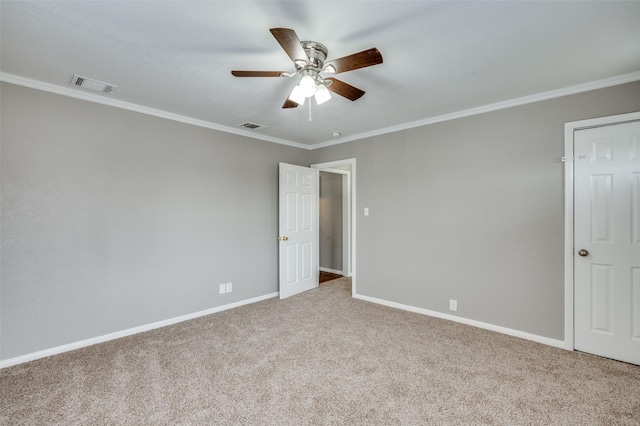 carpeted empty room with baseboards, visible vents, and crown molding