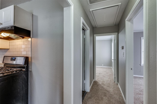 corridor with attic access, baseboards, and carpet flooring