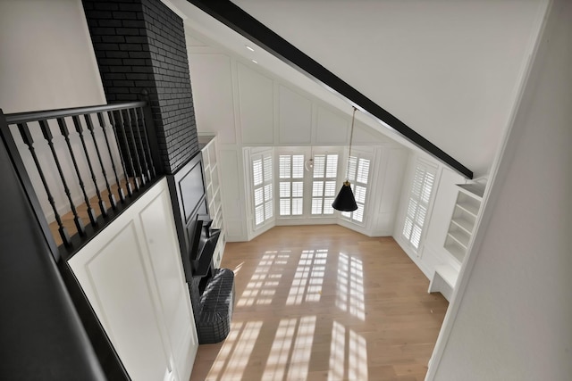 interior space featuring light wood-type flooring, vaulted ceiling, and a decorative wall