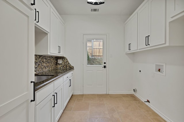 washroom featuring gas dryer hookup, washer hookup, visible vents, cabinet space, and stone finish flooring