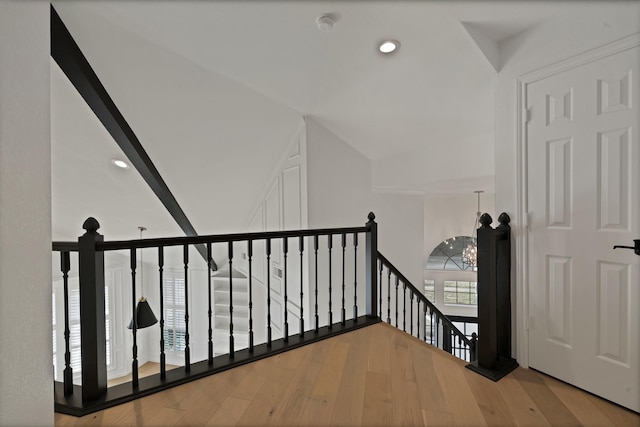 interior space featuring lofted ceiling, recessed lighting, an inviting chandelier, an upstairs landing, and wood finished floors