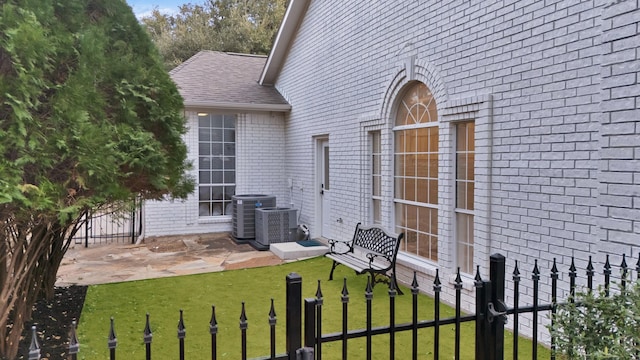 view of yard with fence, central AC, and a patio