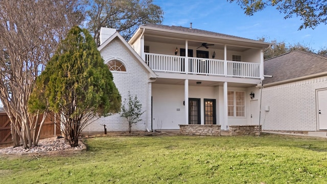 view of front of property with ceiling fan, a balcony, brick siding, fence, and a front yard