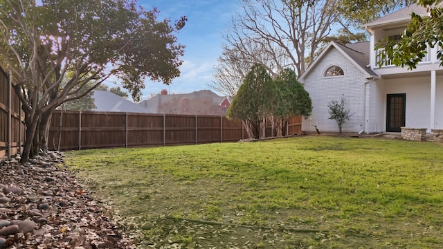 view of yard featuring a balcony and a fenced backyard