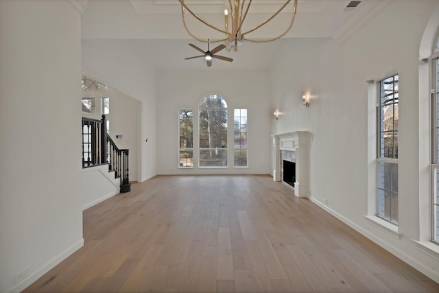 unfurnished living room with light wood-type flooring, a fireplace, baseboards, and stairs